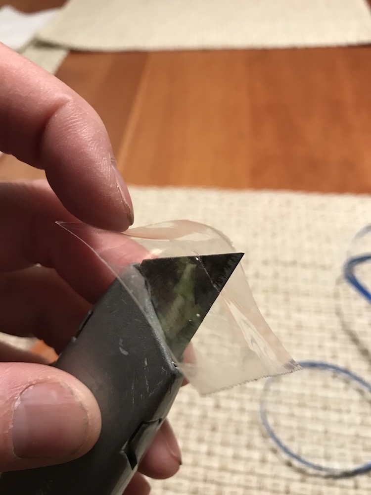 Cut a small slit in center of the square piece of tape.